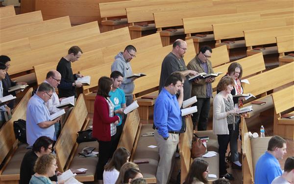 SPST students, faculty, and staff sing from their hymnal books in the pews at the Atonement Lutheran Church