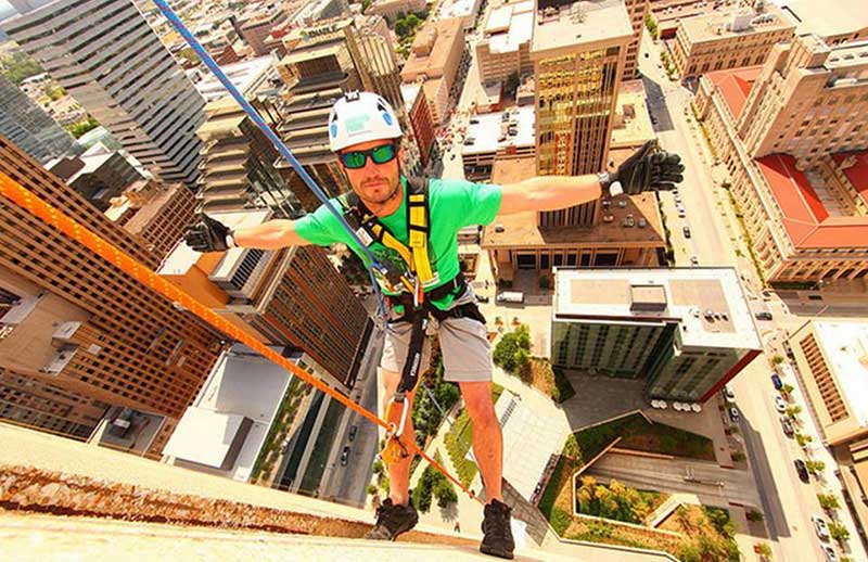 Saint Paul School of Theology alumnus Adam Leathers rappels down a building