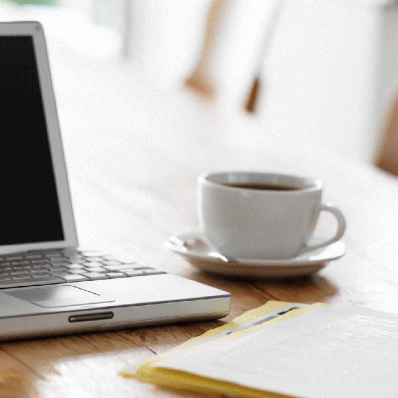 coffee cup sits next to an open laptop