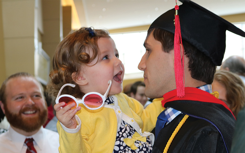 flexx Father holding his daughter after graduating with the help of hybrid and online theology degree