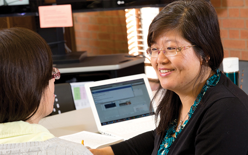 two professors talk together in a classroom