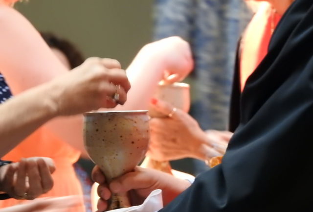 woman offers parishoner wine cup during worship