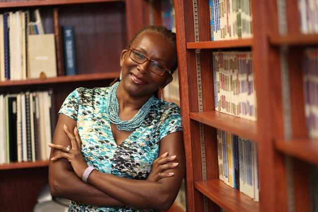 Dr. Angela Simms leans against a bookshelf at Saint Paul School of Theology.