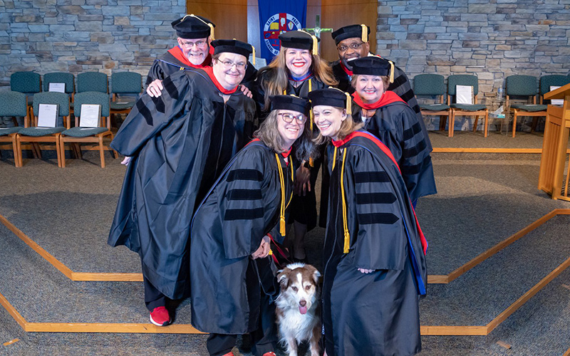 Saint Paul graduates pose in the gowns with service dog