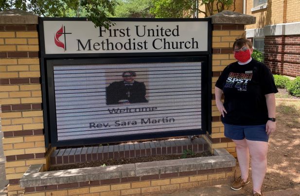 Reverand Sara Martin poses in front of the First United Methodist Church signage