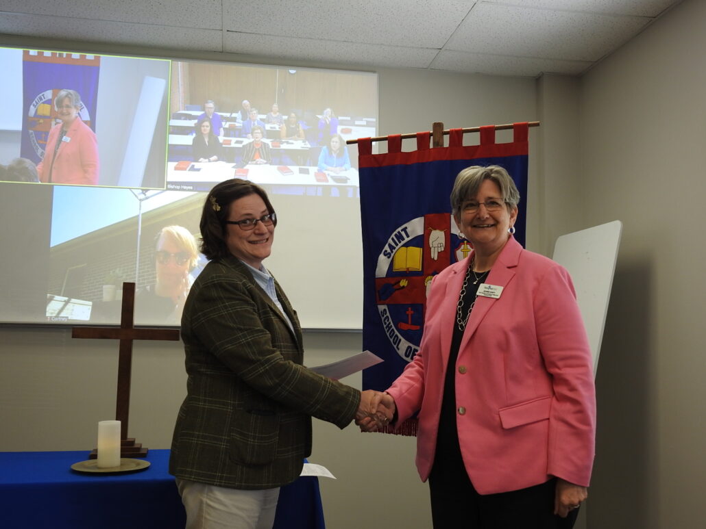 Theology student and faculty member shake hands in classroom